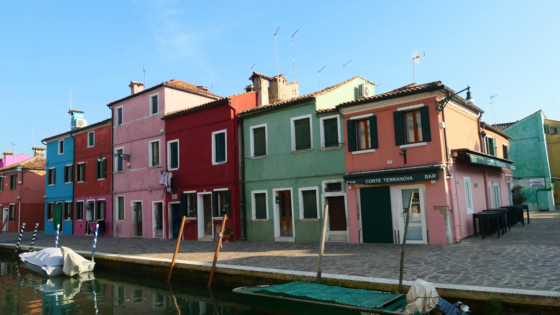 The candy-colored houses of Burano reflected in a still canal