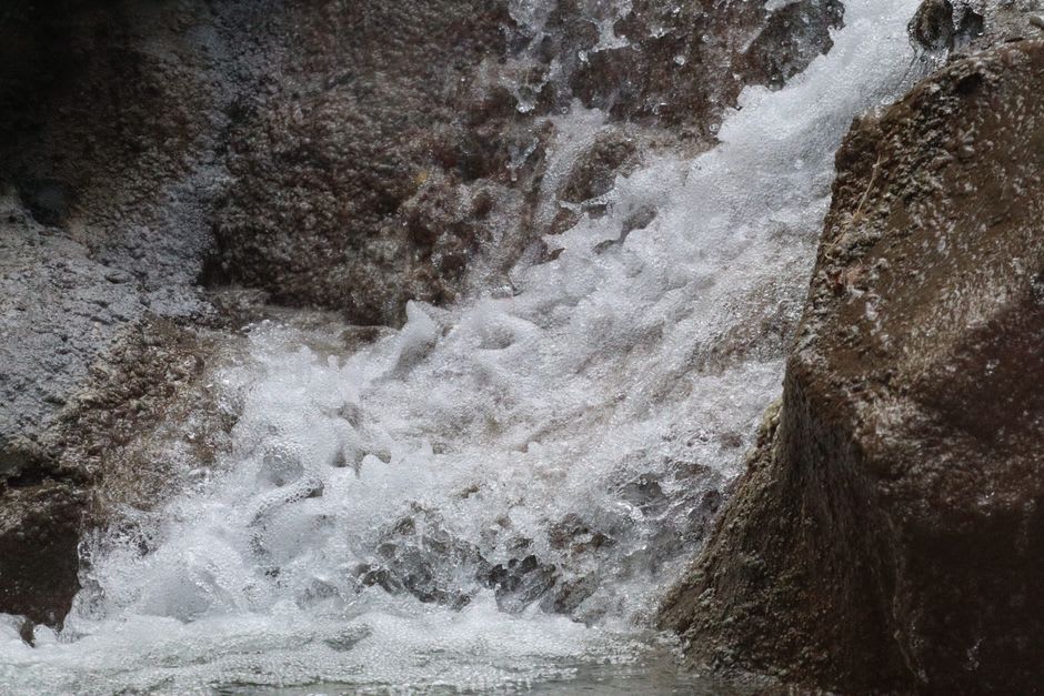 Close-up of cascading water over limestone rock formations at Dunn's River Falls with lush garden vegetation