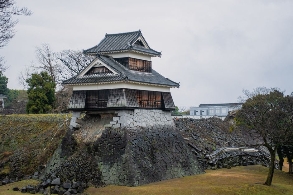 The reconstructed corner turret of Kubota Castle rising above the green trees and old stone walls of Senshū Park in Akita