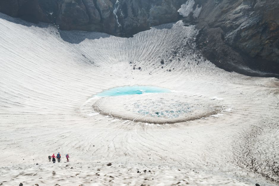 Hikers on the loose scree trail below the summit cone of Asahidake with the Daisetsuzan range beyond