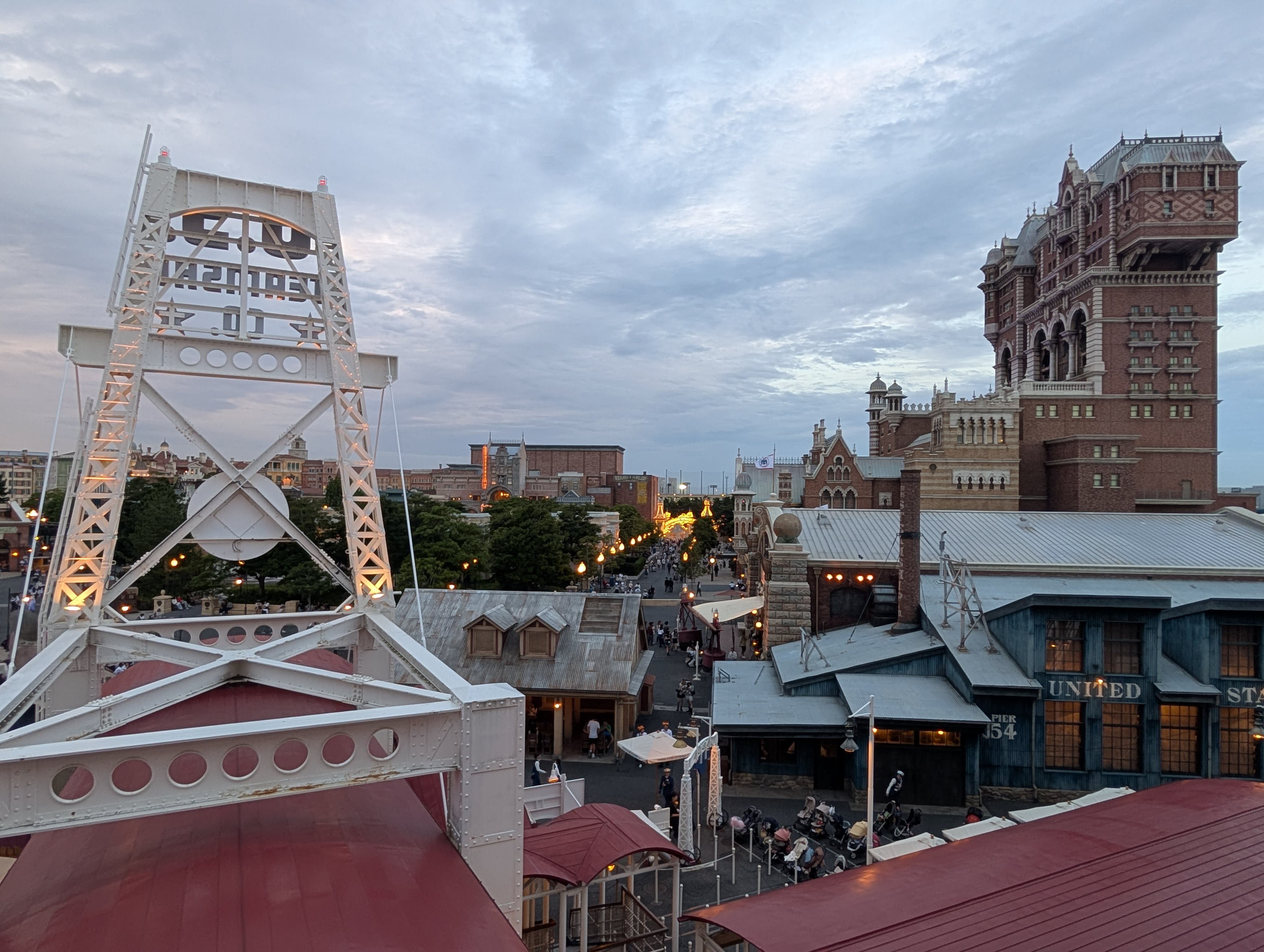 The American Waterfront at dusk — the Tower of Terror rising above rooftops, a steel bridge in the foreground, the warm glow of a New York that never existed but feels remembered