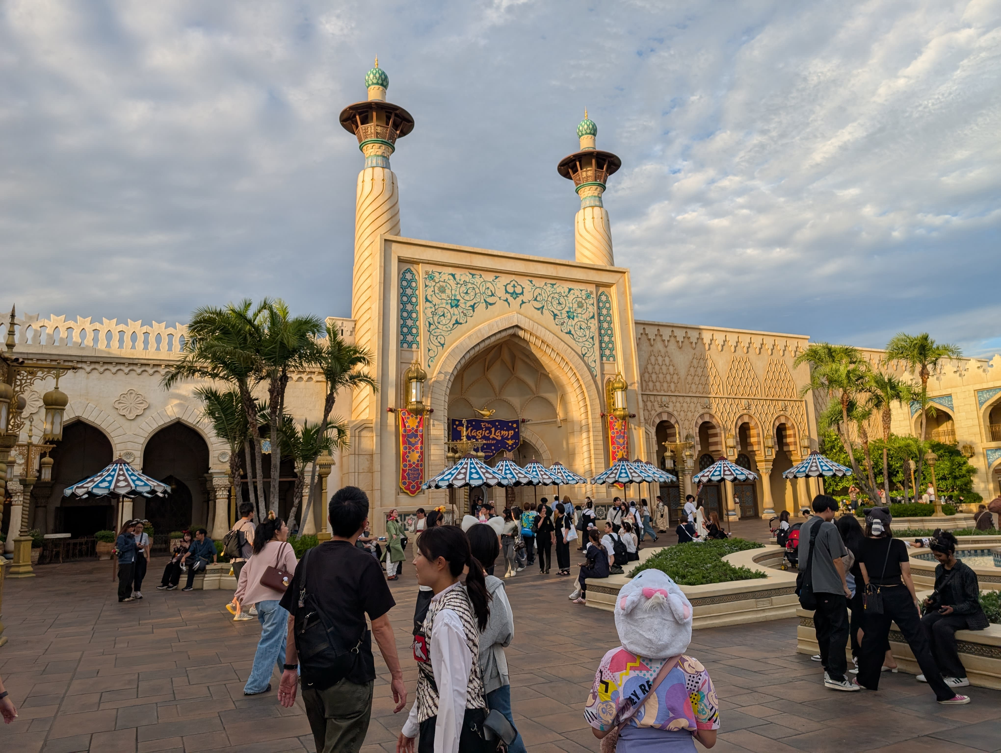 The Arabian Coast palace at DisneySea — golden minarets, ornate tilework, arched doorways, visitors walking through a plaza that feels transported from another world