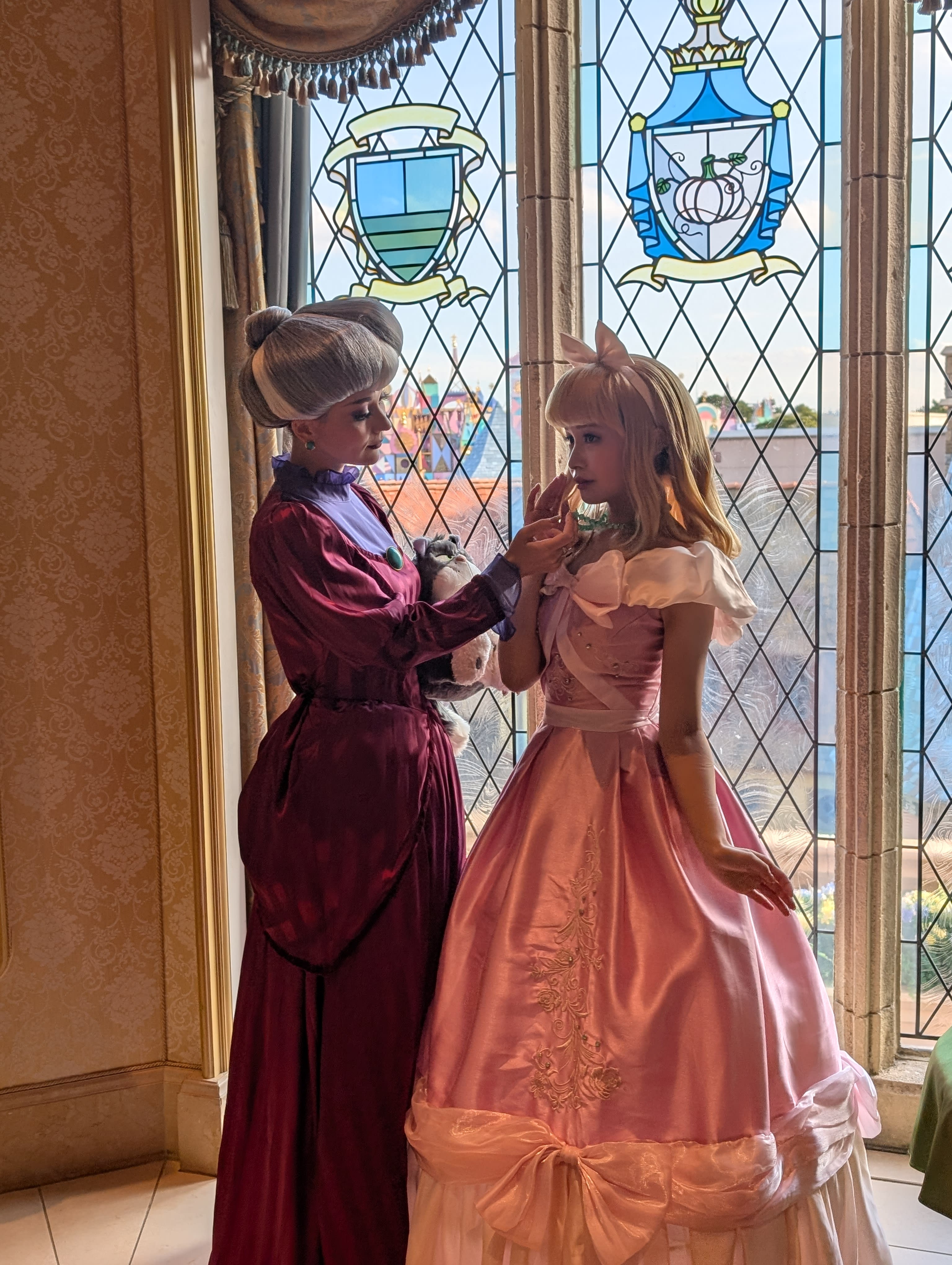 The Fairy Godmother and Cinderella in the castle gallery — full period costumes, stained-glass windows, a scene that blurs the line between theatre and belief