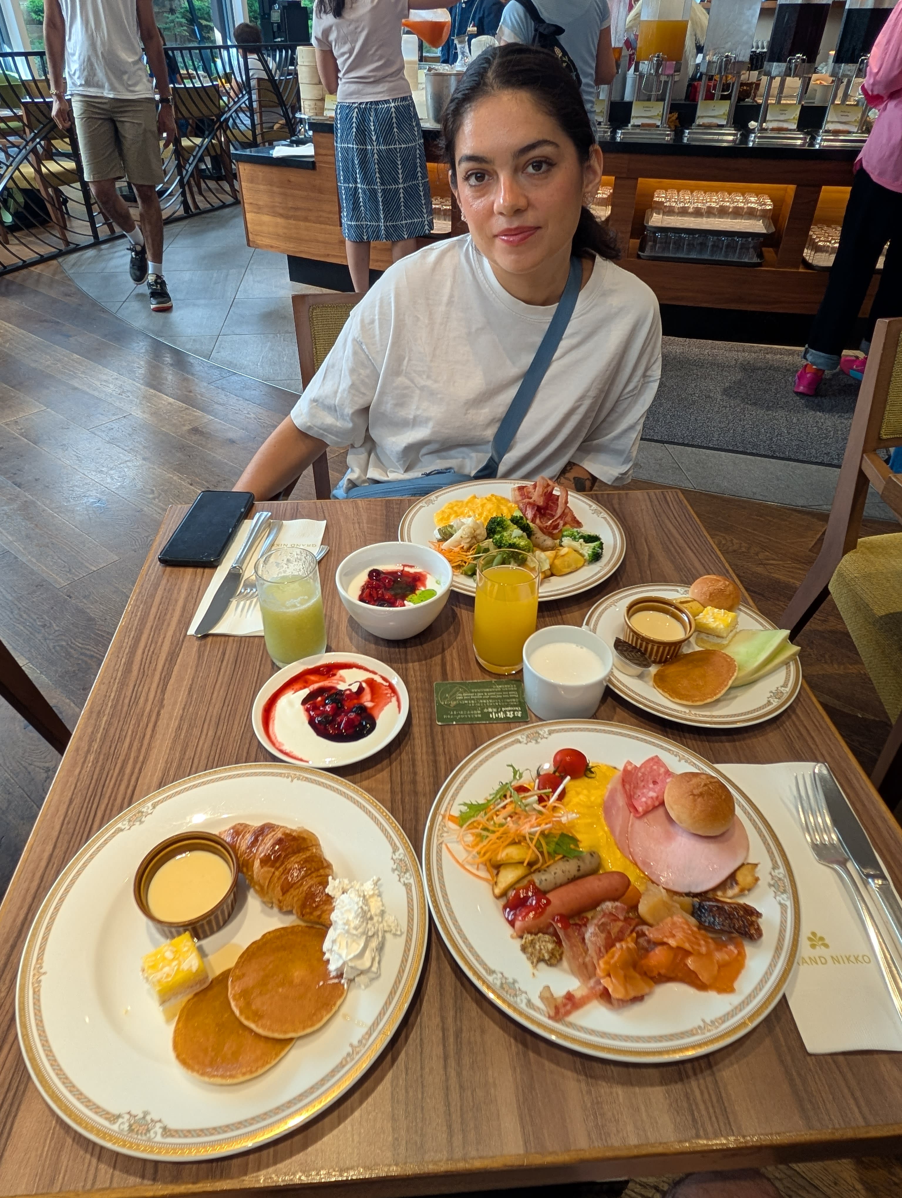 Lia at the Grand Nikko breakfast buffet before DisneySea — pancakes, eggs, fruit, orange juice, and the focus of an athlete preparing for competition