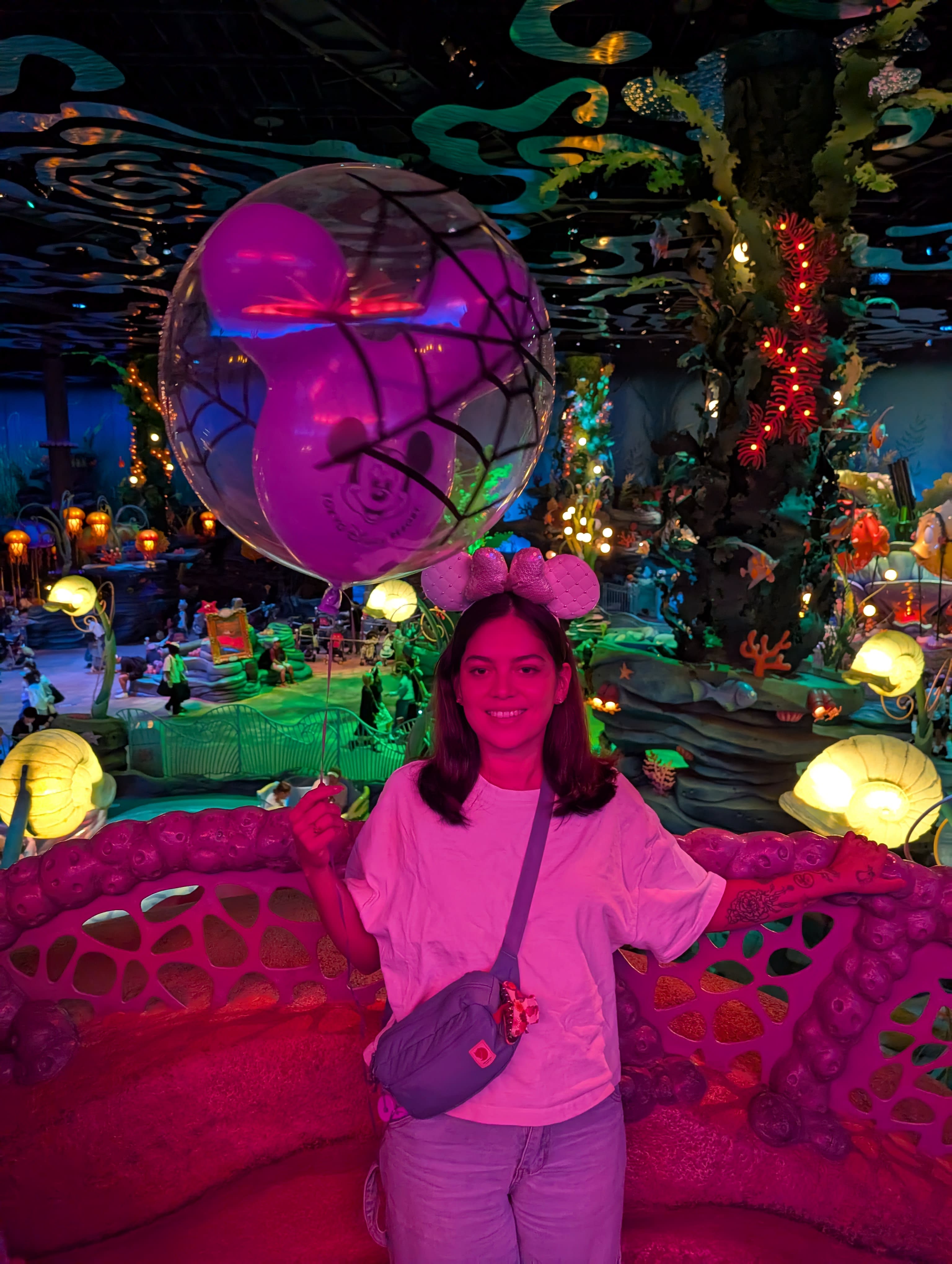 Lia inside Mermaid Lagoon — purple and pink light, coral and shells glowing around her, the Halloween balloon overhead, a world that feels more real than it has any right to