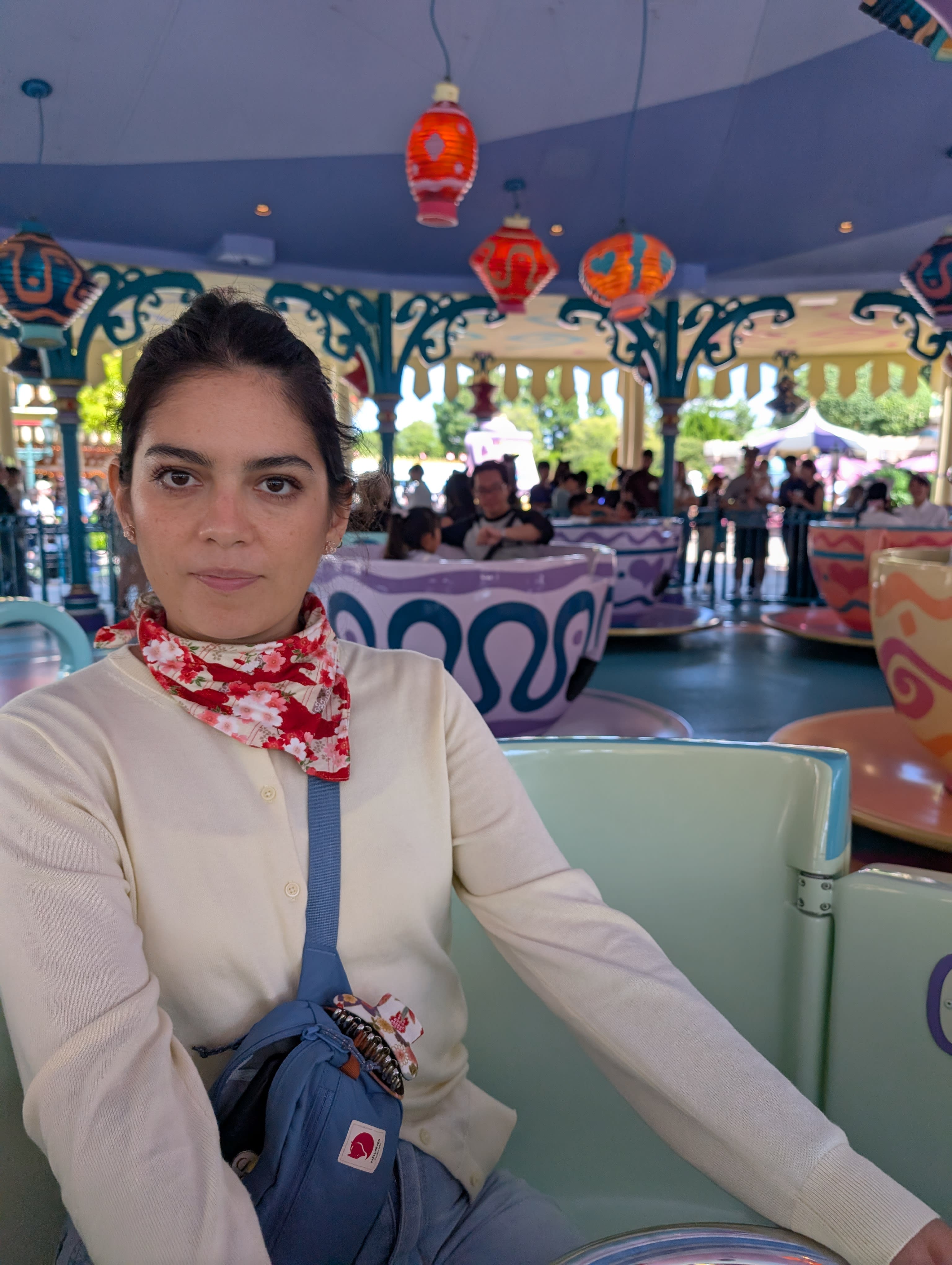 Lia on the Mad Tea Party teacups ride — pastel cups, Chinese lanterns overhead, the composed expression of someone having more fun than she will admit