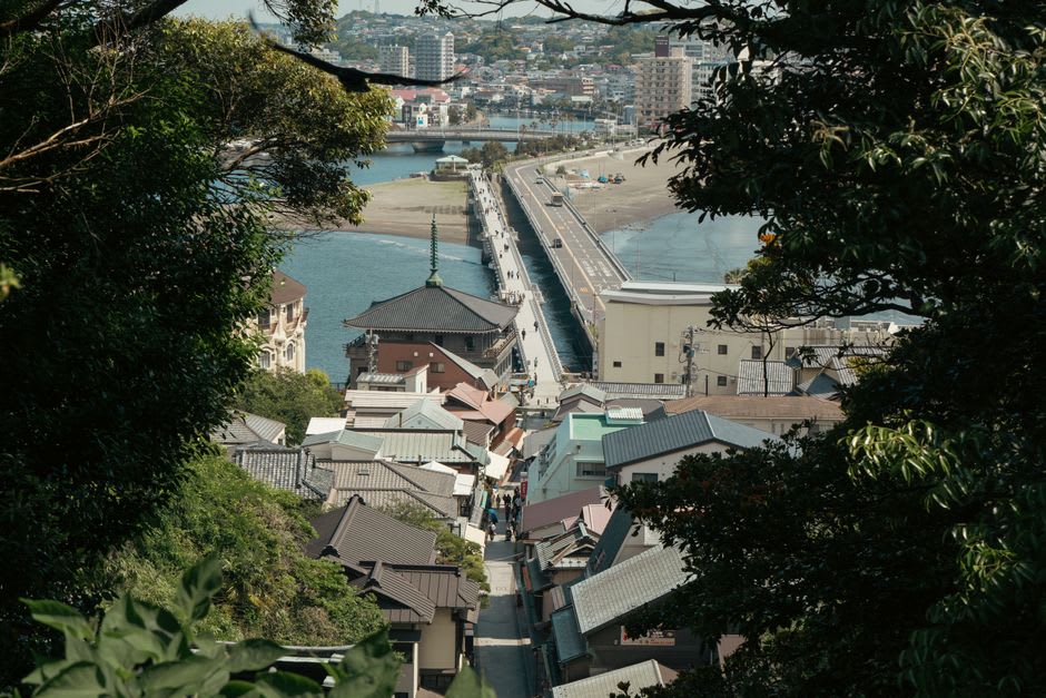 The long low bridge to Enoshima crowded with visitors, the green wooded island rising ahead under a bright sky