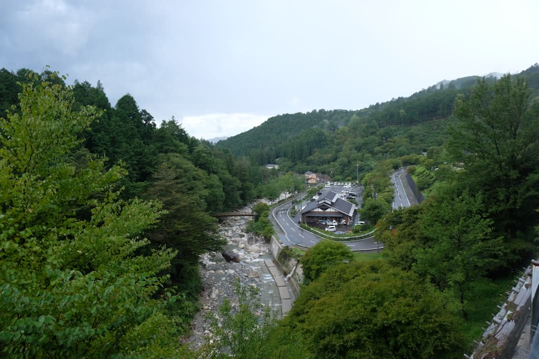 Steam rising off an outdoor rotenburo bath at a Gero ryokan, wooden fences and autumn maples framing the mountain view
