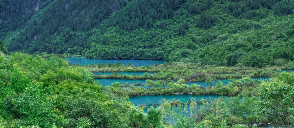 Broad turquoise-to-cobalt sheet of Bishonuma pond with the grey crater of Mount Bandai behind