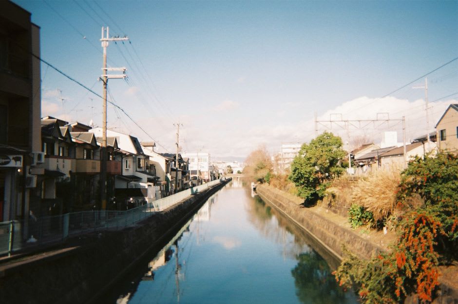 The tiered stone basins of the Sogi-sui spring in Gujō-Hachiman, clear water flowing through them beside an old wooden house