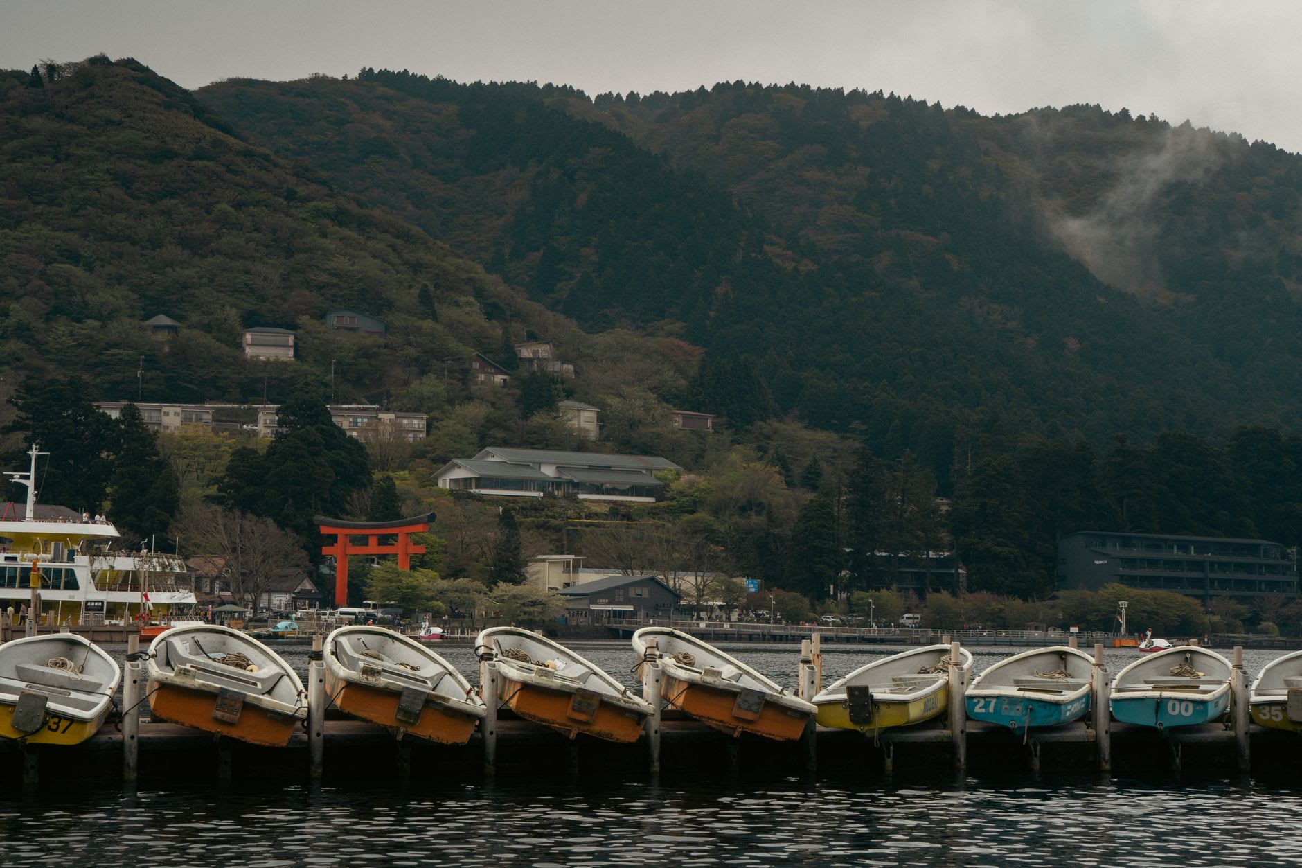 Outdoor rotenburo bath at dawn in Hakone, steam rising over the still lake with Mount Fuji in the background