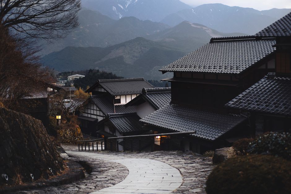 A carved wooden eave detail on an old merchant house in Hida-Furukawa, dark timber joinery against a white wall