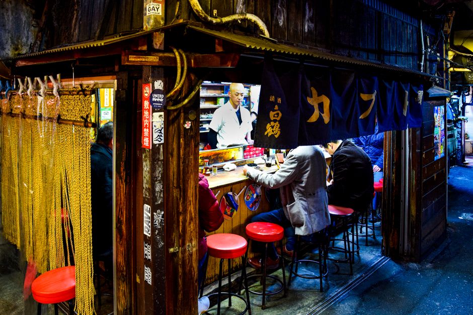 The nostalgic Edo-style shopfronts of Okage-yokochō near Ise Jingū, wooden storefronts and hanging noren curtains lining a stone-paved lane crowded with visitors