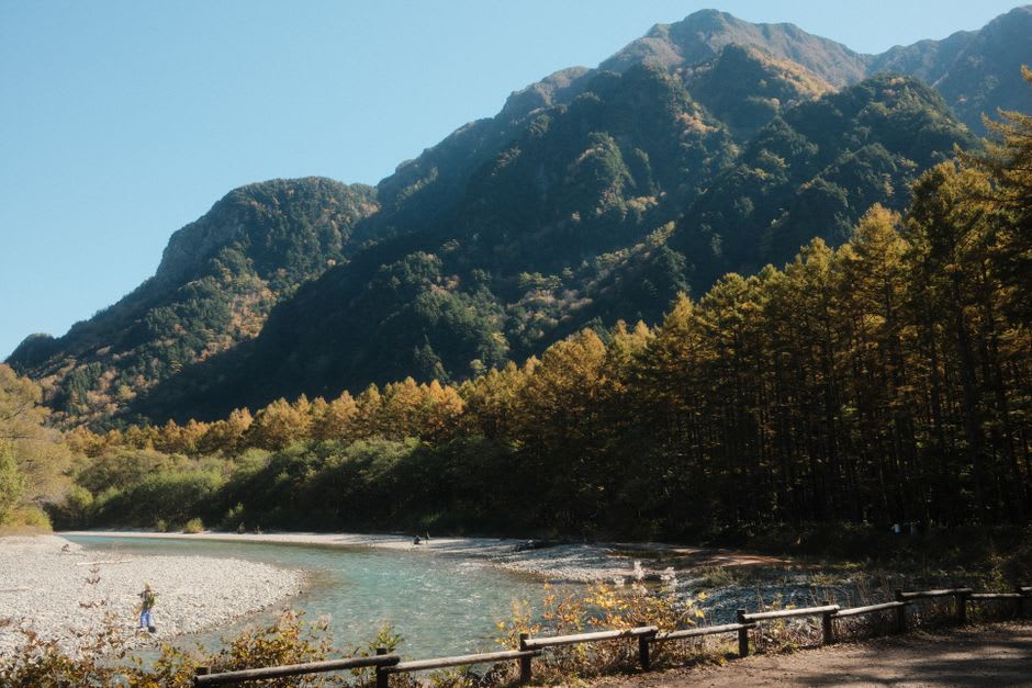 A steaming riverside public foot bath at Jōzankei, visitors soaking their feet with the autumn-coloured gorge behind