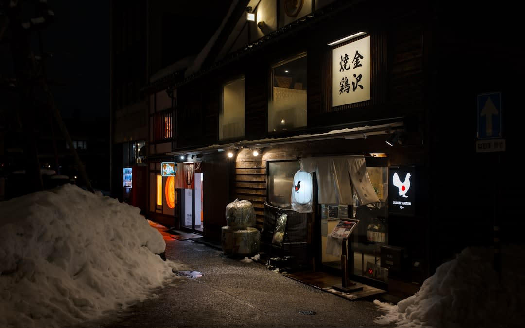 A traditional wooden public bathhouse glowing at dusk in the Kaga Onsen villages