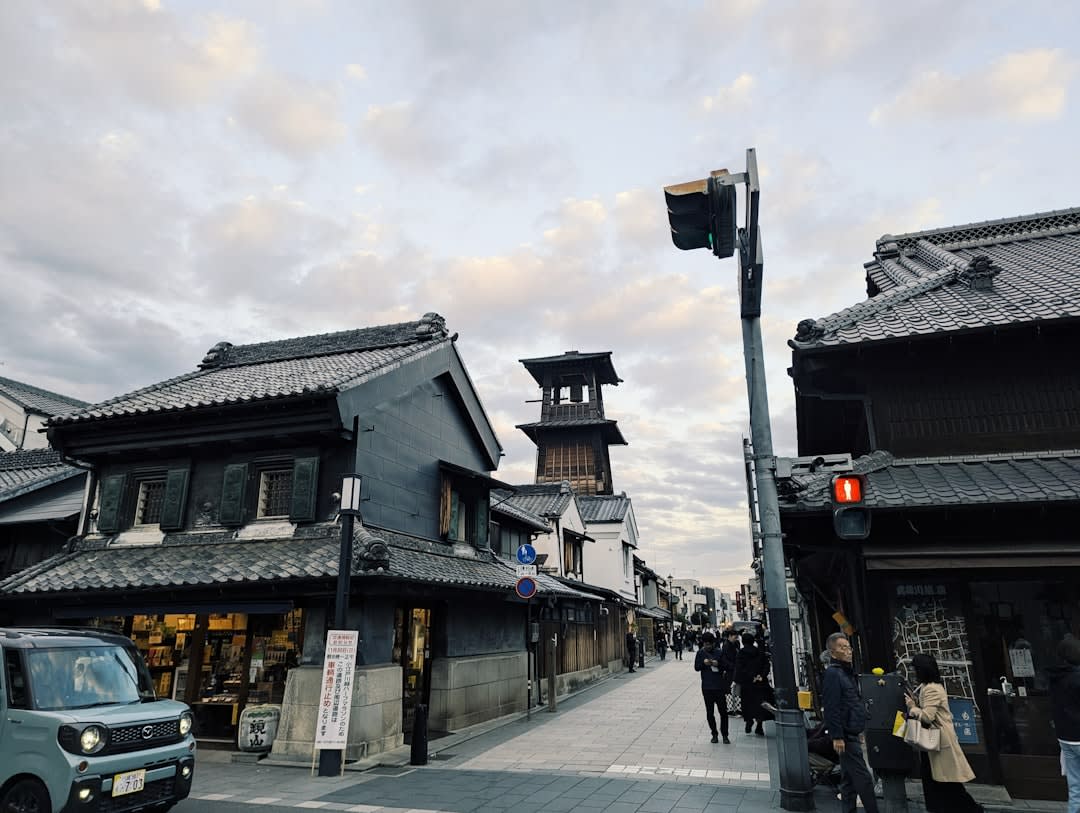 The main kurazukuri street of Kawagoe lined with dark-walled Edo-period merchant warehouses, heavy grey tiled roofs and a few visitors walking below