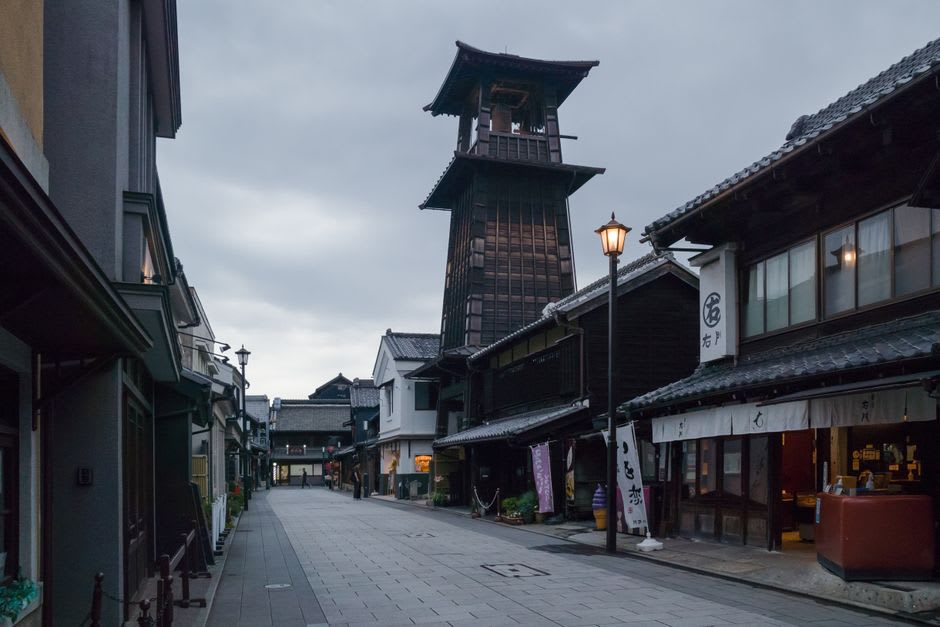 The wooden three-tiered Toki-no-Kane bell tower rising above the rooftops of Kawagoe against a pale overcast sky