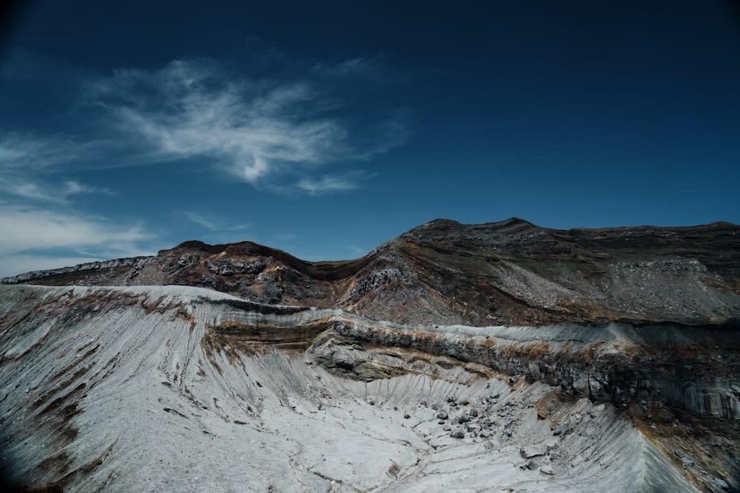The vast green caldera floor of Mount Aso, grazing land rolling toward the distant crater-rim mountains under a wide sky