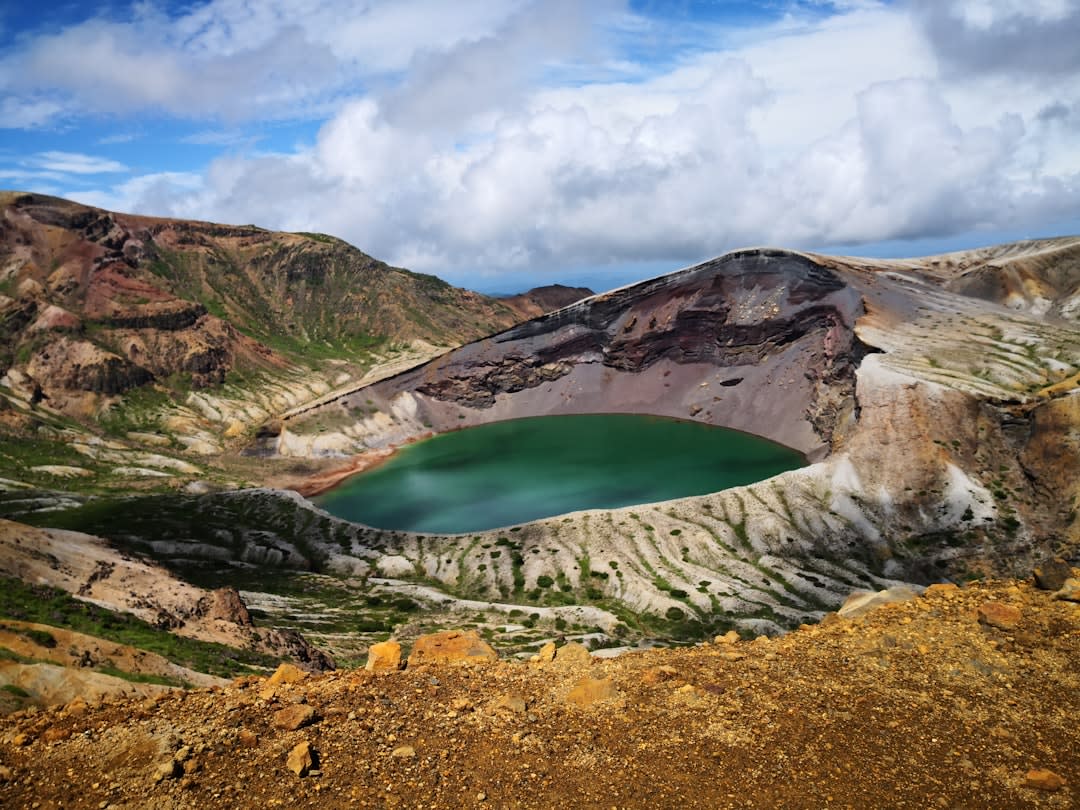 The steaming red-brown dome of Shōwa-Shinzan rising beside Mount Usu near Lake Toya, faint volcanic vapor drifting from its cracks