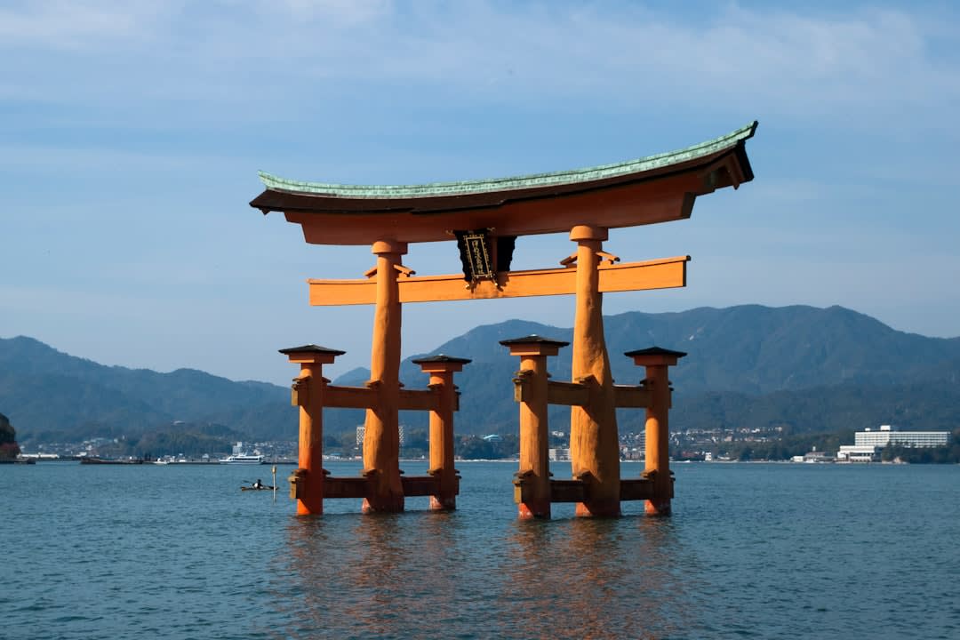 The floating torii gate and stilted halls of Itsukushima Shrine reflected in the still water at high tide