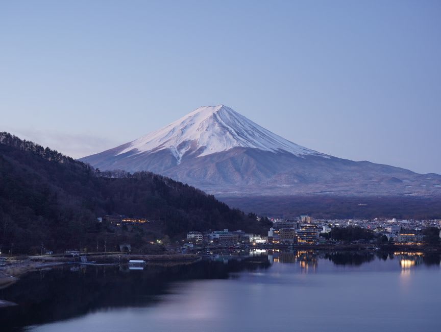 Clear kayak drifting over the deep blue water of Lake Motosu with the summit in the distance