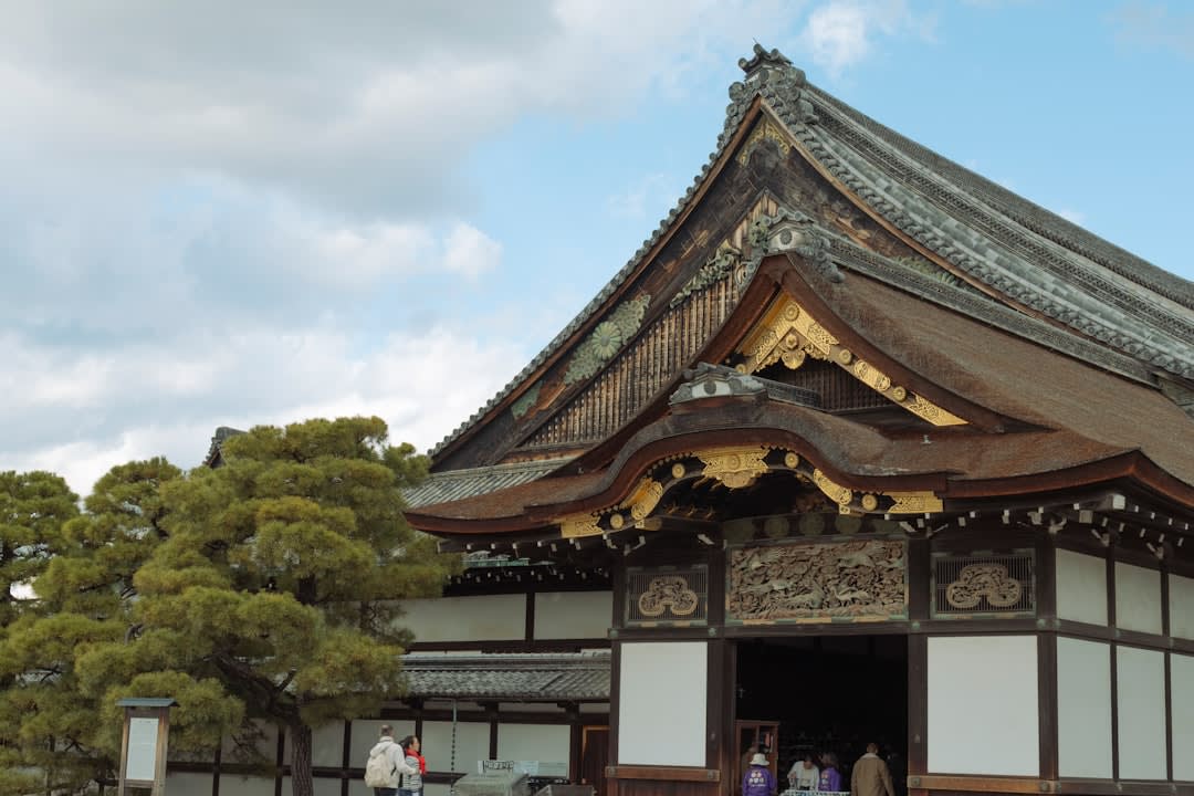 The immense wooden main hall of Zenkō-ji with worshippers on the stone forecourt, incense smoke rising before it