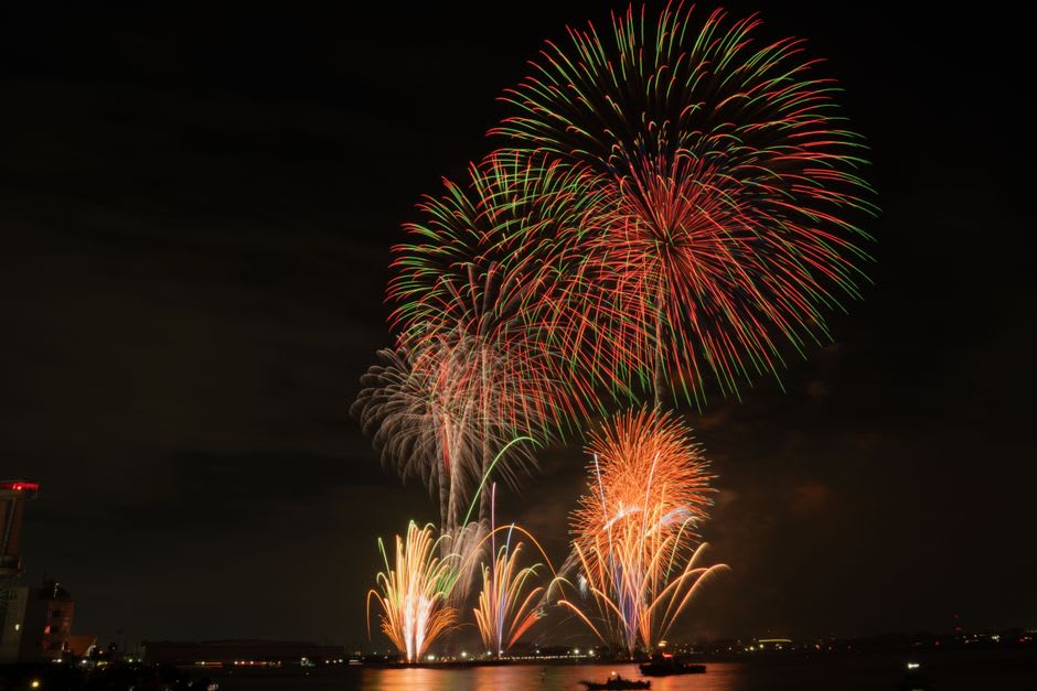 The Phoenix fireworks sequence spreading in a wide arc of gold over the Shinano river at Nagaoka