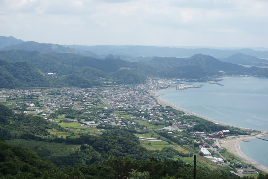 The projecting 'peek into hell' rock shelf at Nokogiriyama jutting out over a sheer quarried cliff, a visitor at the railing with Tokyo Bay far below