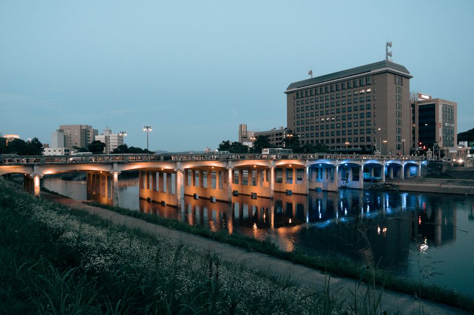 Cherry-lined banks of the Otogawa river at dusk with Okazaki Castle illuminated