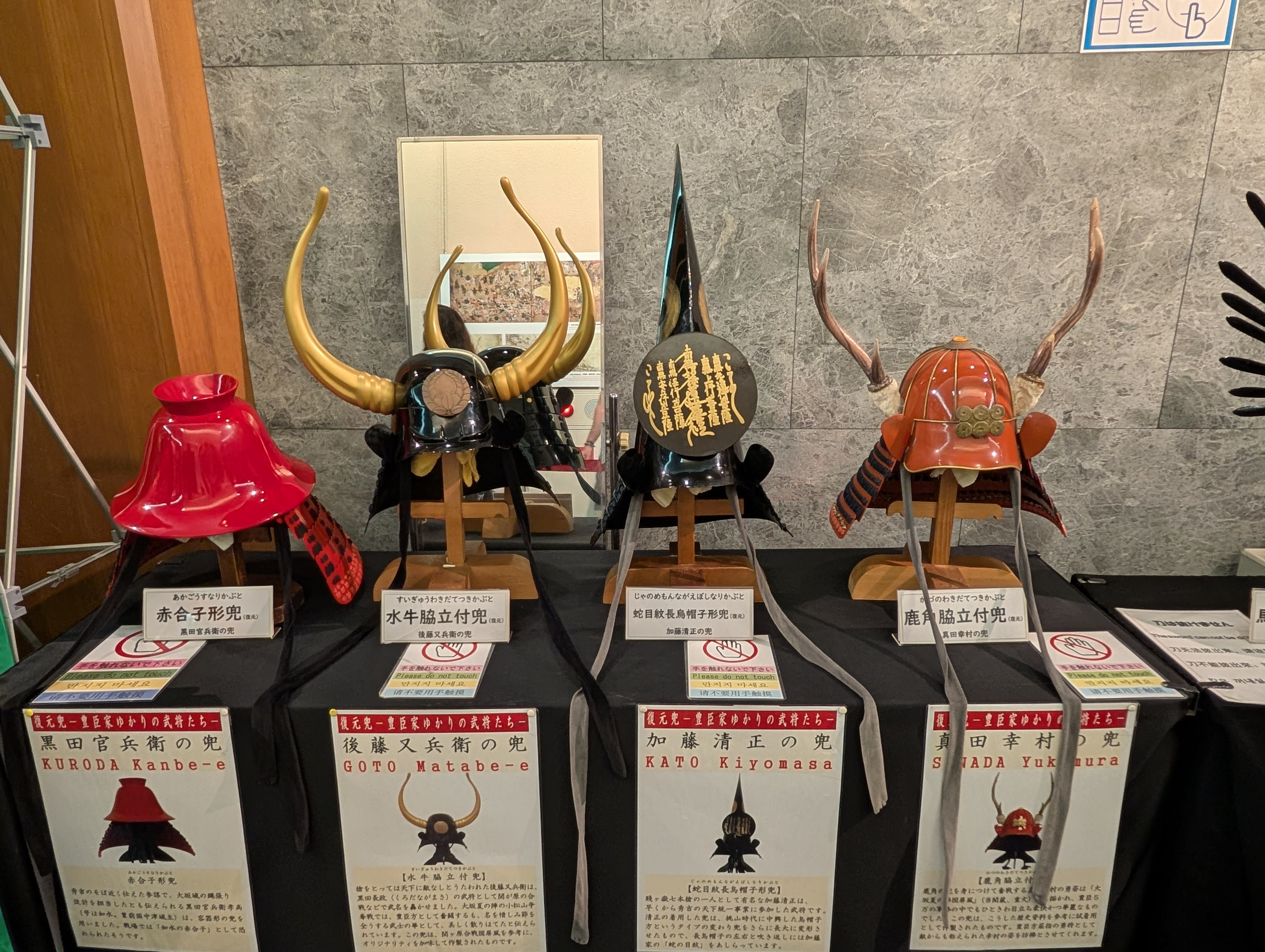Samurai helmet display inside Osaka Castle — four elaborate helmets with gold horns, crescent moons, and antlers, each more dramatic than the last