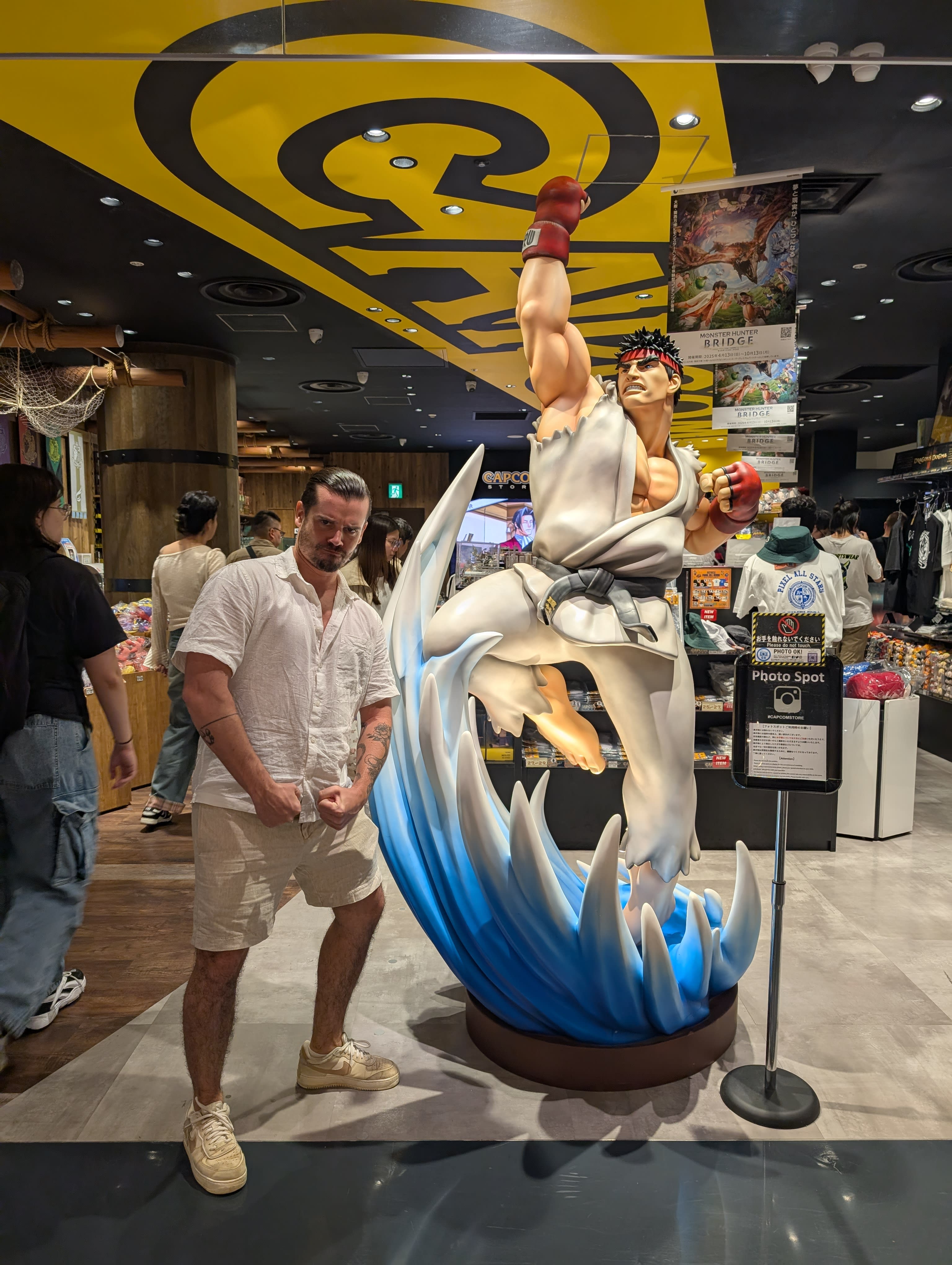 Pierre next to a life-sized Ryu statue from Street Fighter at the Capcom store — the fighter mid-shoryuken, Pierre maintaining a neutral expression that fools nobody