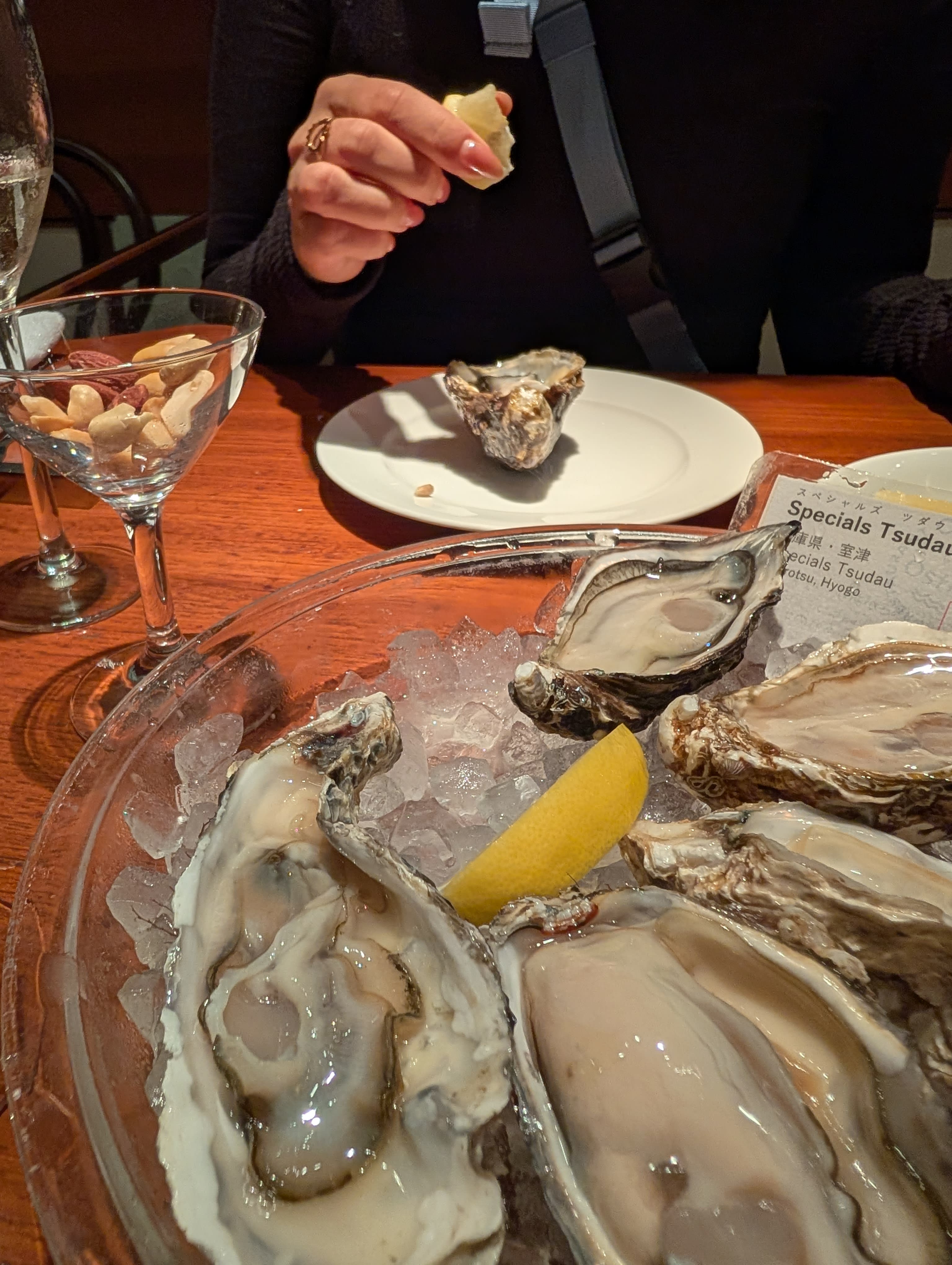 Fresh oysters on ice with champagne at a Ginza oyster bar — lemon wedges, wine glasses, and the quiet elegance of a place that knows what it is doing