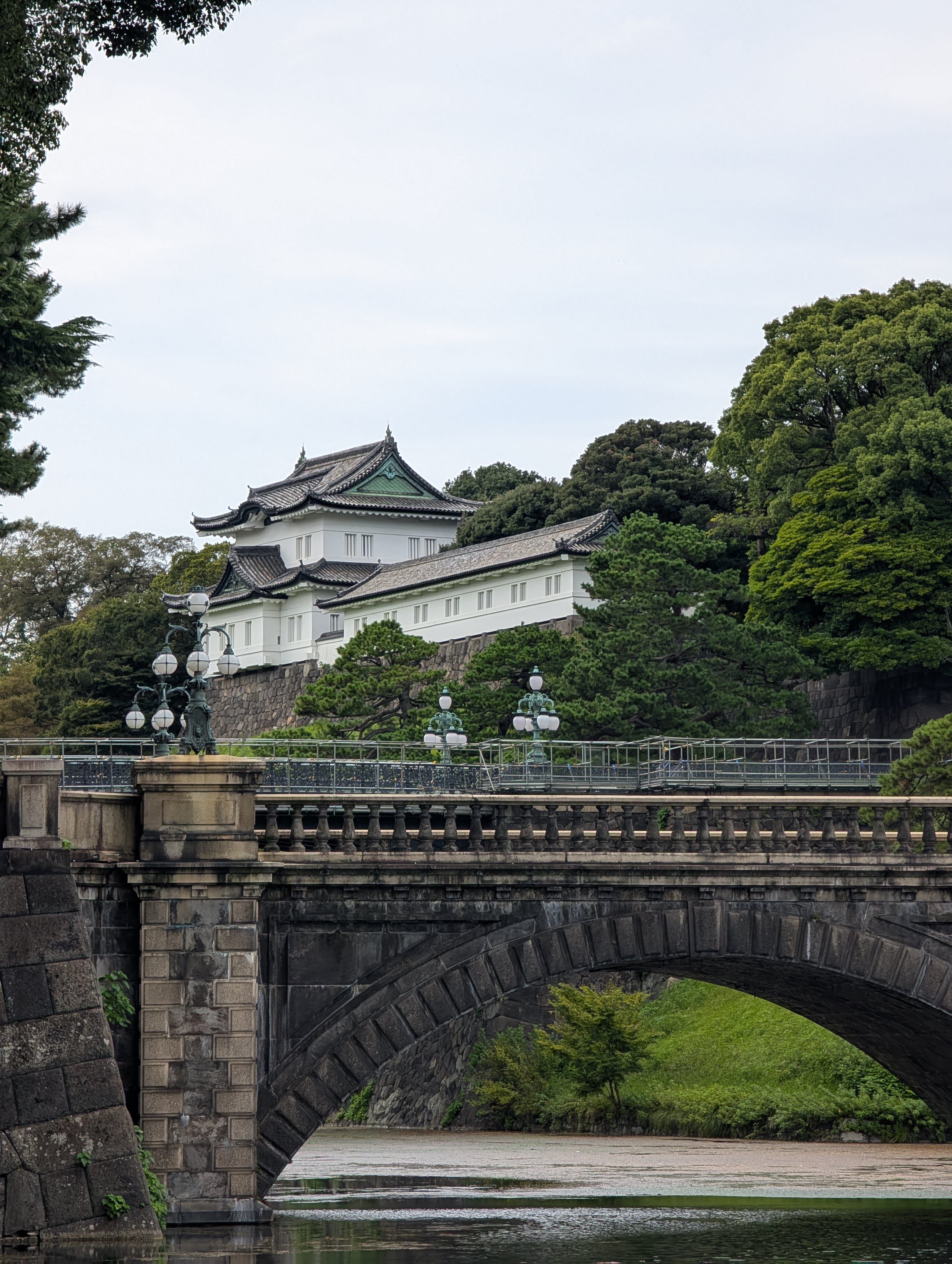 The Nijubashi bridge at the Imperial Palace — stone arches over the moat, the white palace buildings and dark-tiled roofs rising above ancient trees