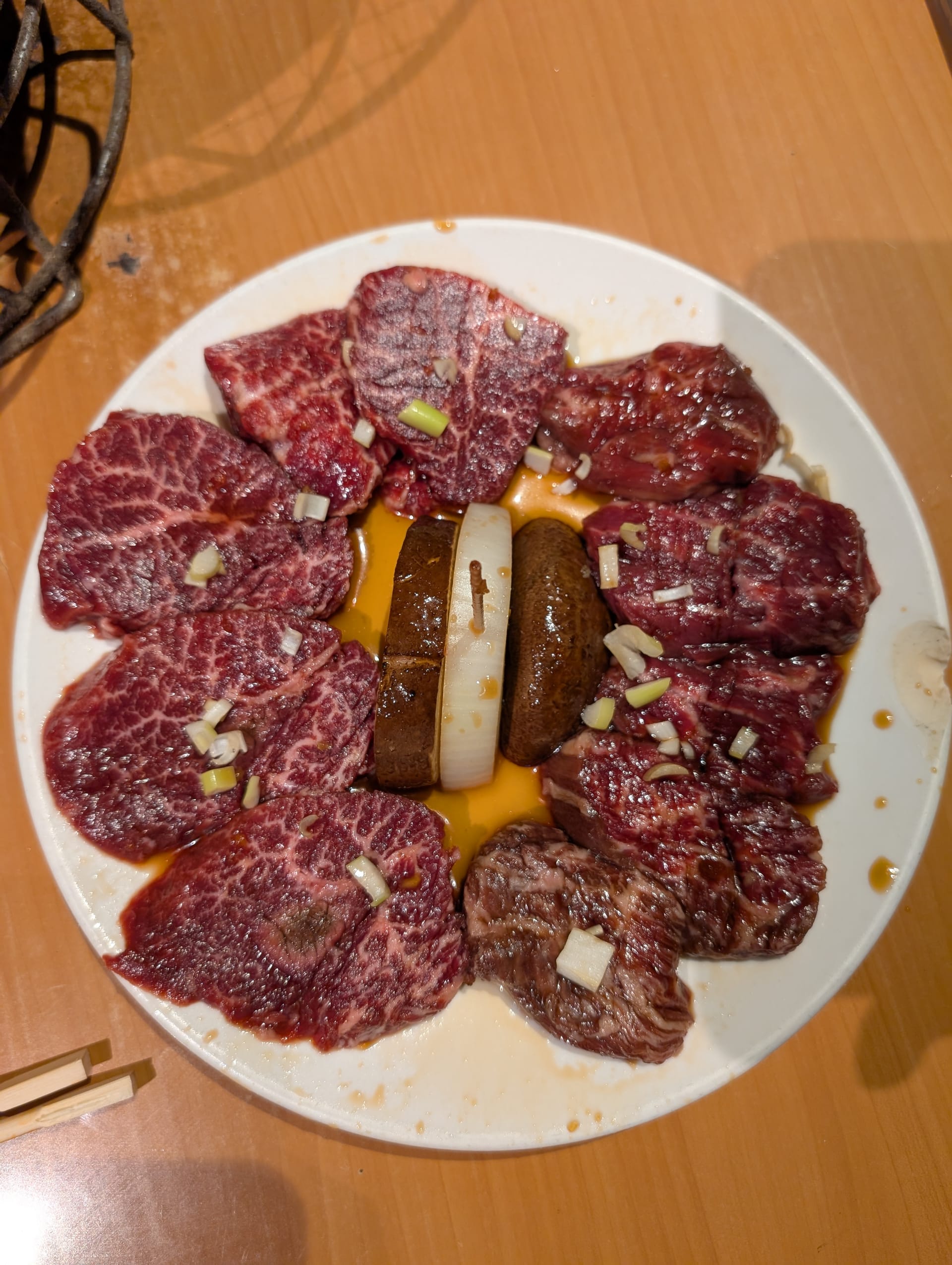 A plate of wagyu yakiniku — marbled beef cuts arranged in a circle around egg yolk, ready for the charcoal grill