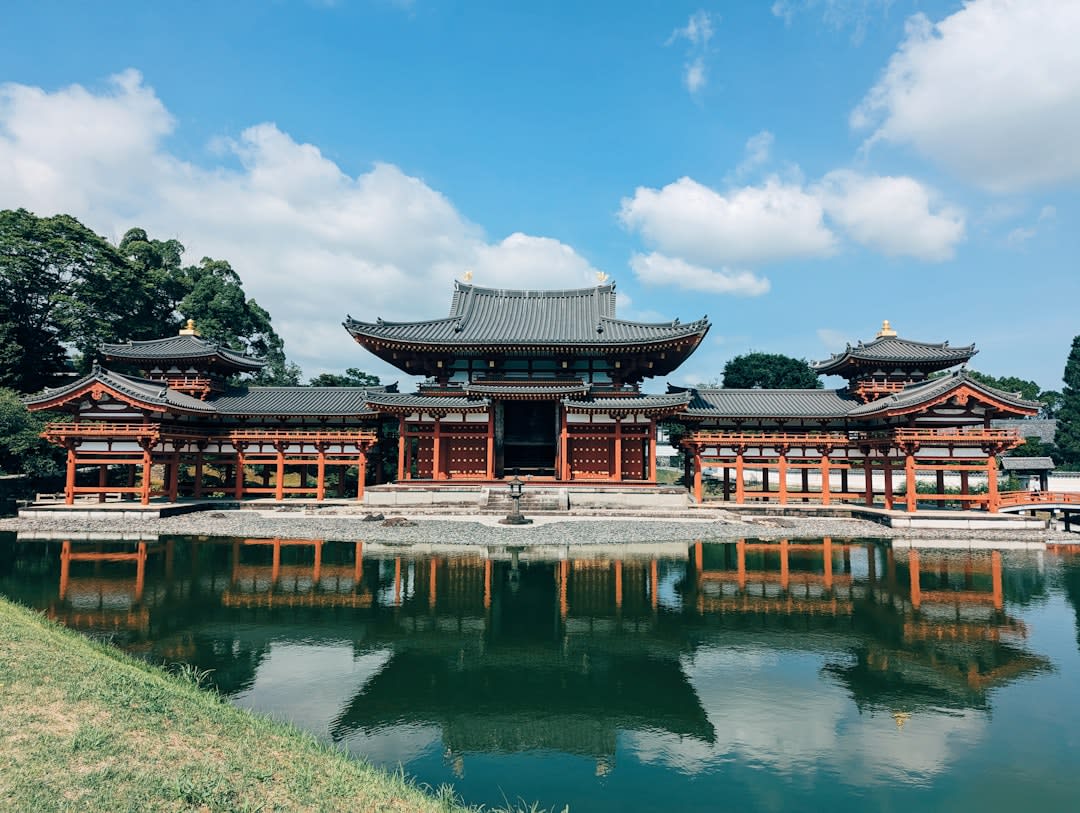 The fast green Uji river crossed by a wooden bridge, tea houses and wooded hills along the bank in soft afternoon light