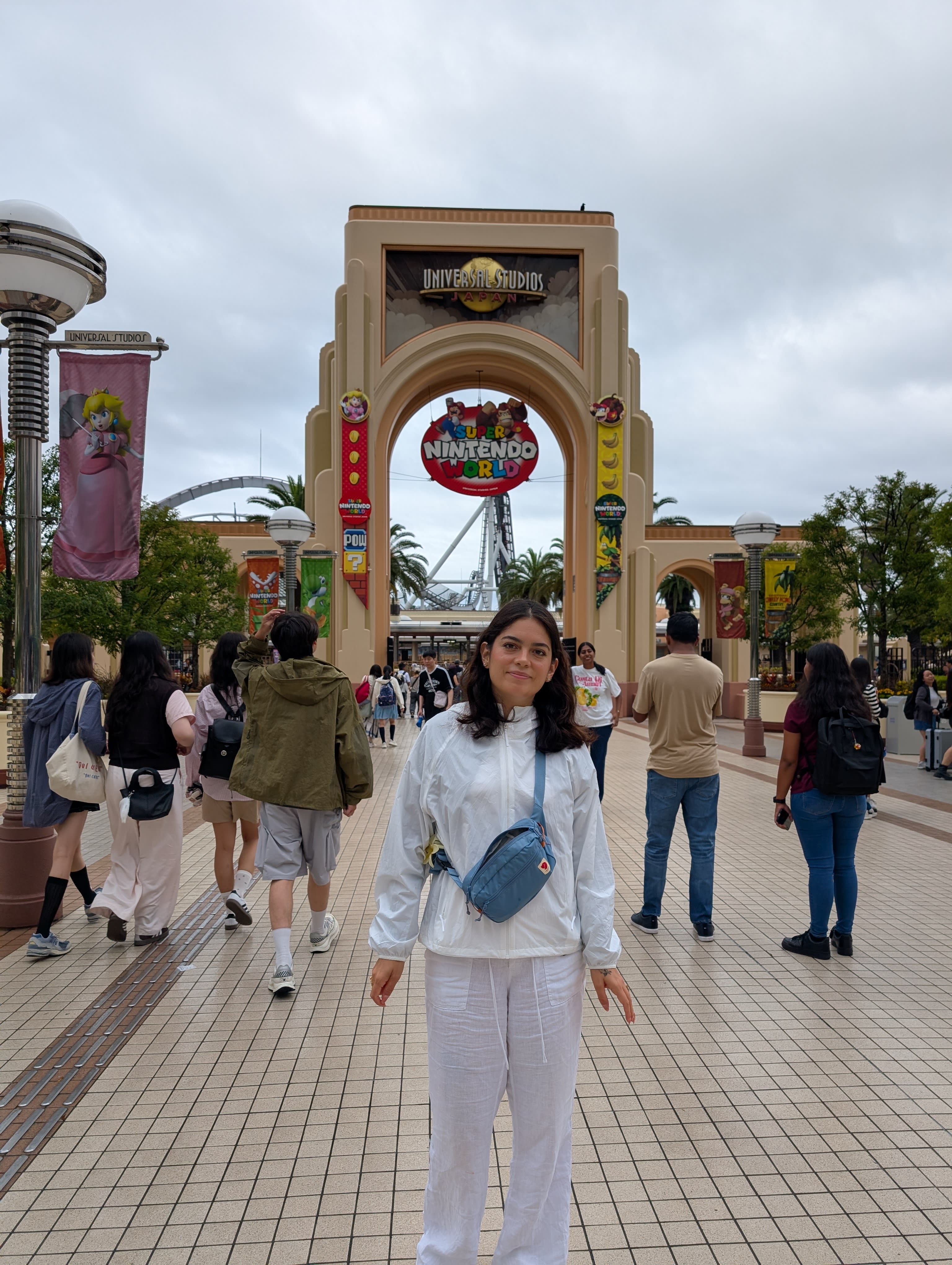 Lia at the Universal Studios Japan entrance — the park gate behind her, the Nintendo World banner visible above, the look of someone who has been vindicated