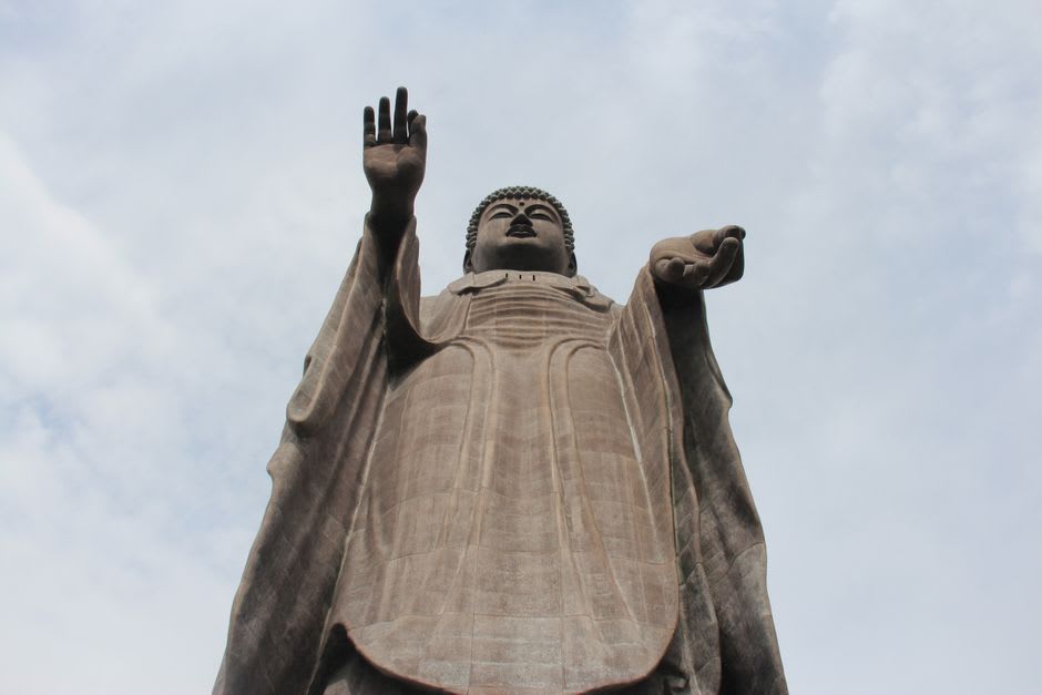 The full height of the Ushiku Daibutsu bronze Buddha seen from its base, robes falling in vast folds