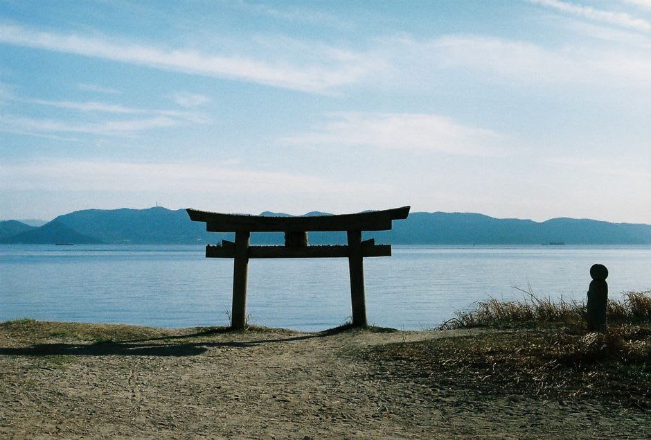 The weathered vermilion torii and stone lanterns of Warei Shrine under trees