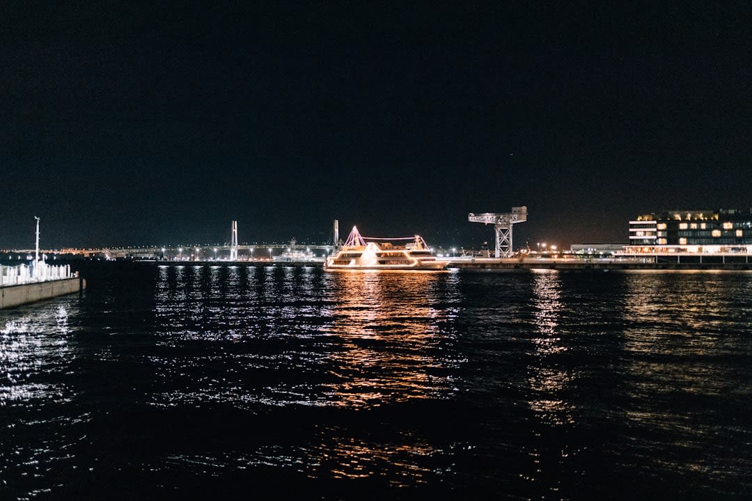 The Cosmo Clock 21 ferris wheel glowing in shifting colors over the Minato Mirai waterfront at night, reflections streaking the harbor water
