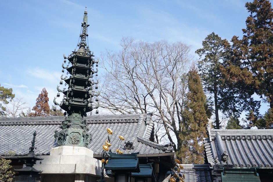 Pilgrims in white robes walking beneath the great five-storey pagoda of Zentsū-ji