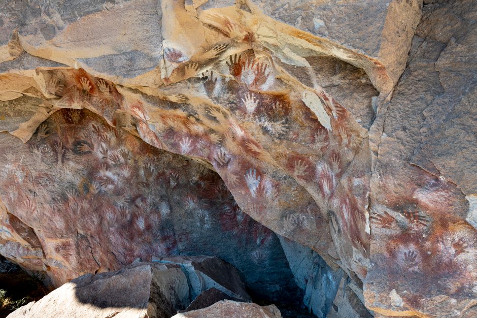 Faded red rock paintings of eland and geometric shapes on the sandstone cliffs of Tsodilo Hills