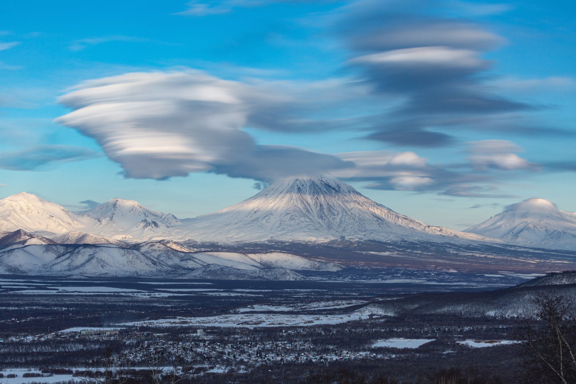 Campos de lava solidificada en los flancos inferiores de la Klyuchevskaya, basalto negro contrastando con parches de nieve y el cielo gris ceniza por encima