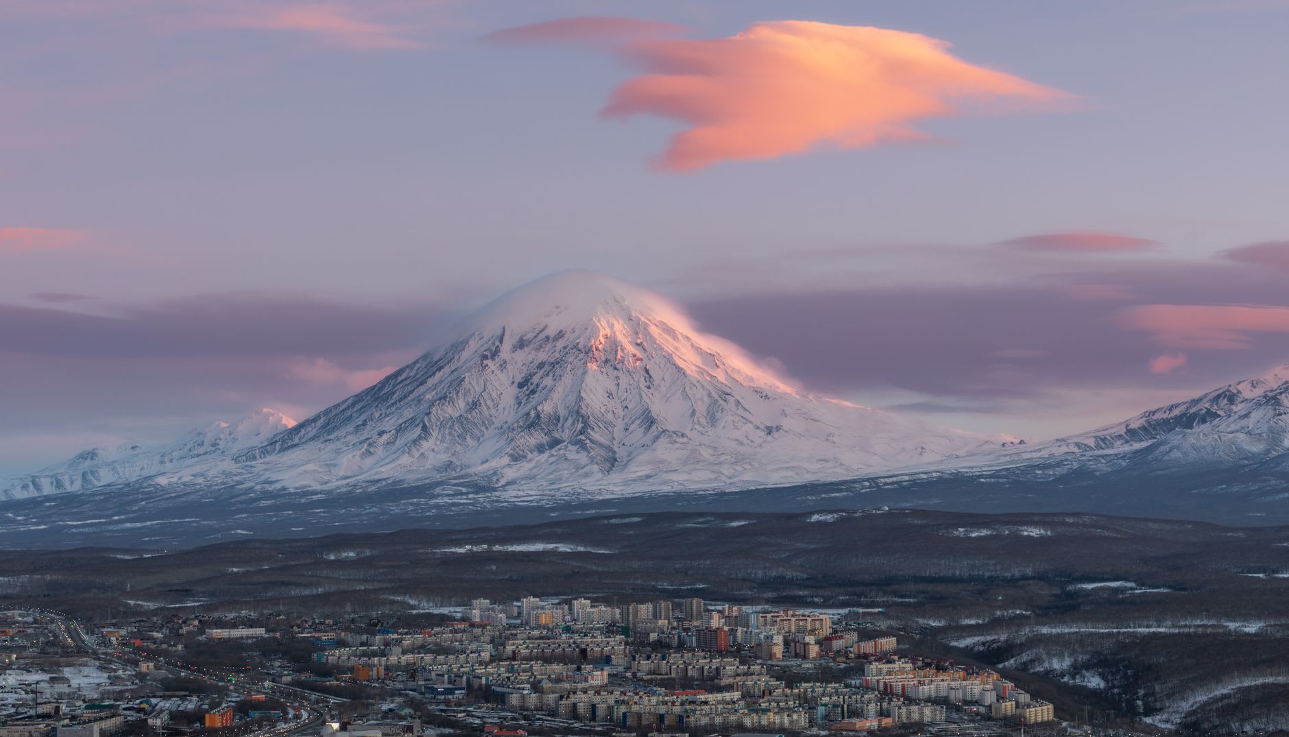 The Petropavlovsk waterfront with fishing boats moored at the harbour and volcanic peaks in the distance