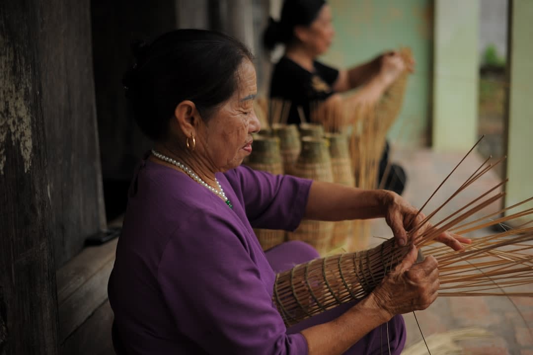 Group of women weaving pandanus mats together under a shaded shelter on Arorae island