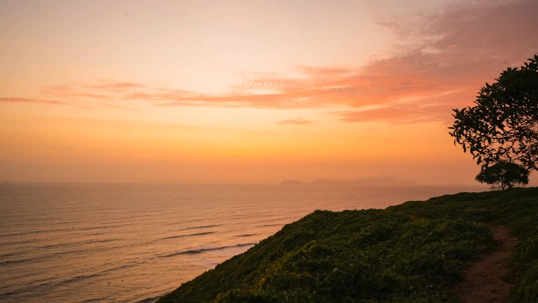 Niños en un camino costero en la isla Beru al atardecer, palmeras cocoteras en silueta contra un cielo anaranjado