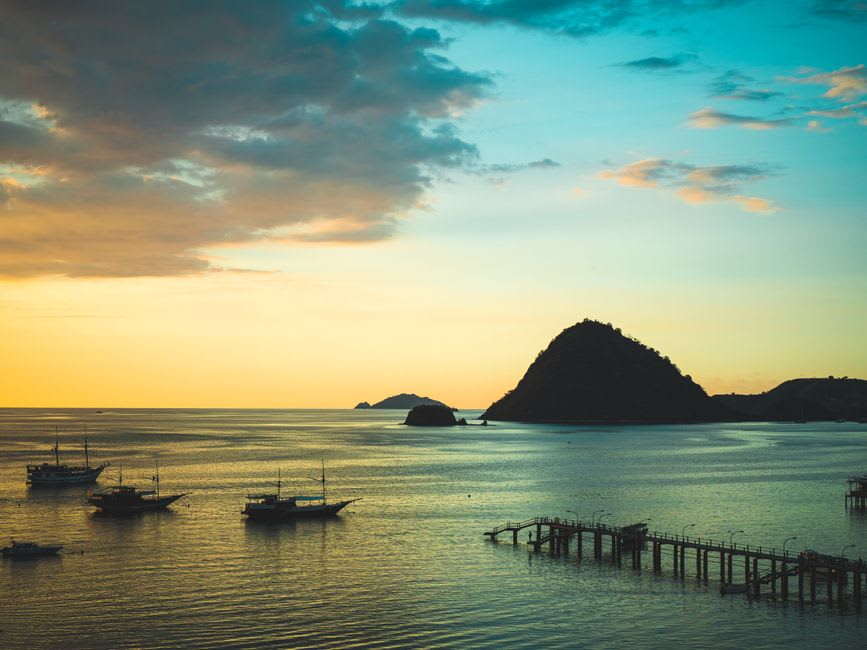 Sunset light over the calm water surrounding Kanawa Island with a wooden guesthouse silhouette