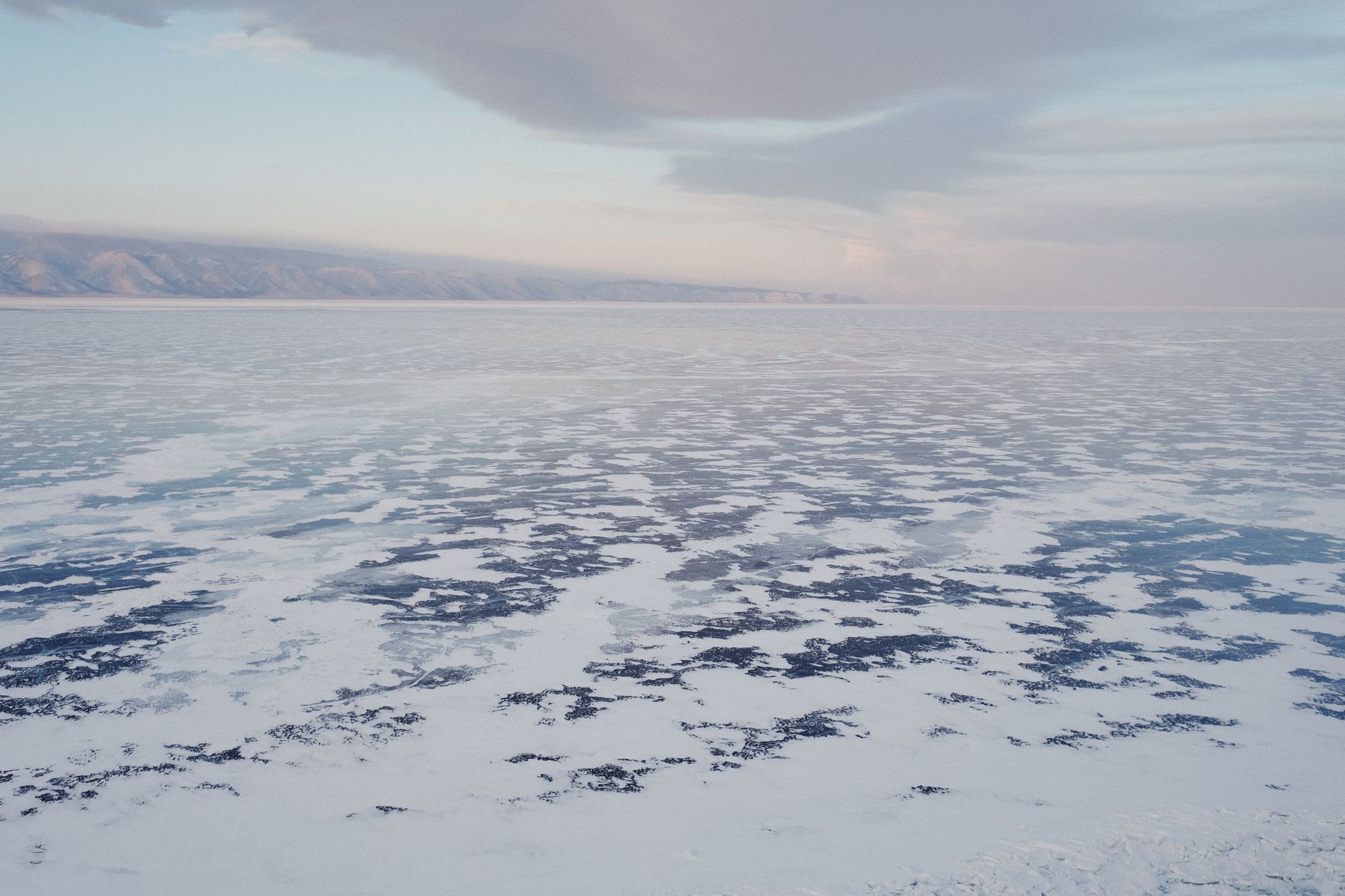 Pressure ice hummocks on the shore at Bolshoe Goloustnoe, blue-green ice ridges catching morning sun against the flat white of the open lake