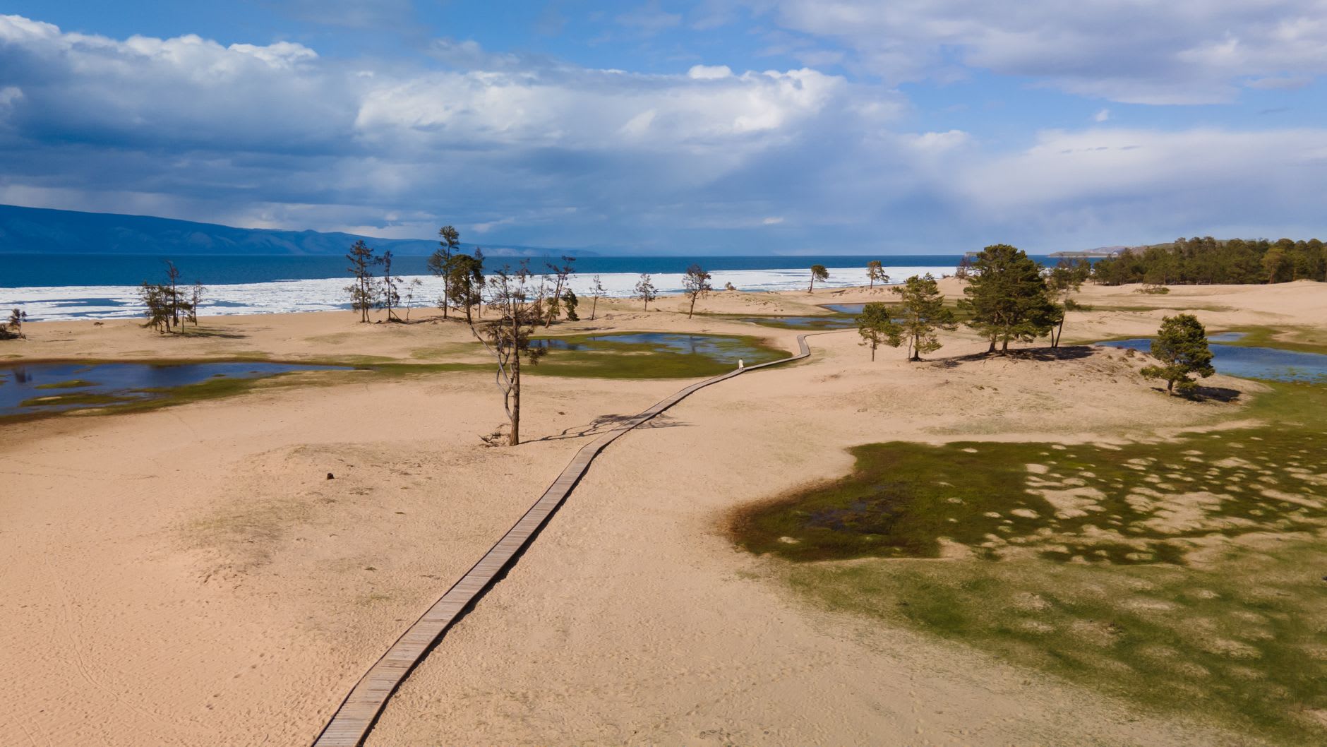 The train crossing a stone viaduct above Baikal, the lake glittering in afternoon light far below