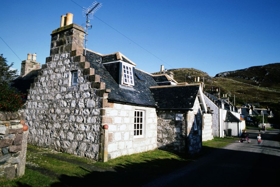 Des cottages en ardoise autour du green du village d'Elterwater avec les Langdale Pikes s'élevant derrière