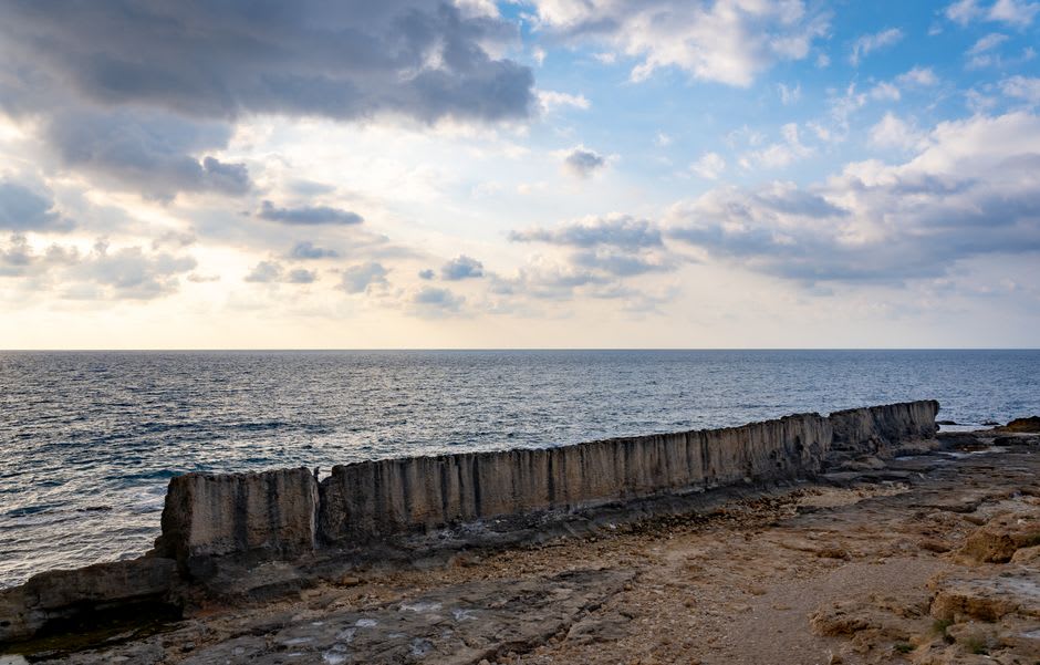 Adolescentes saltando desde el antiguo muro fenicio al Mediterráneo al atardecer
